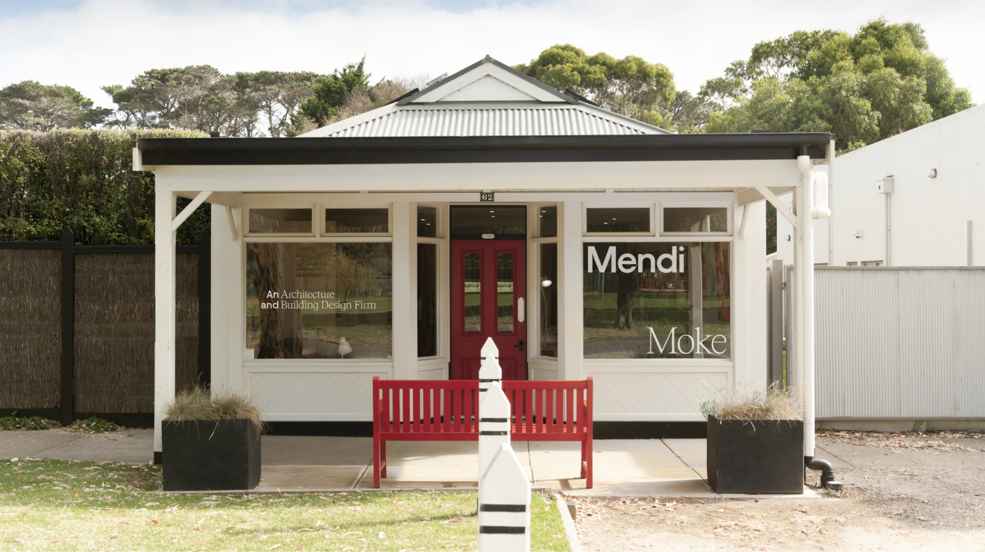 Branding Design for Mendi Moke, the studio exterior with window signage and a red bench